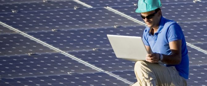 Man on standing solar panel roof with laptop