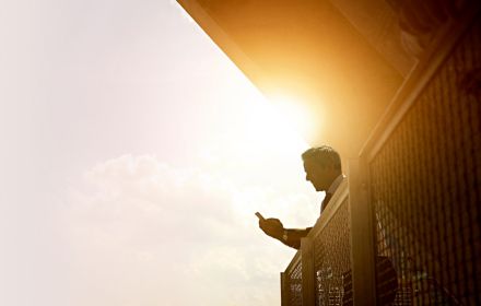 Businessman using cell phone on a bright sunny day