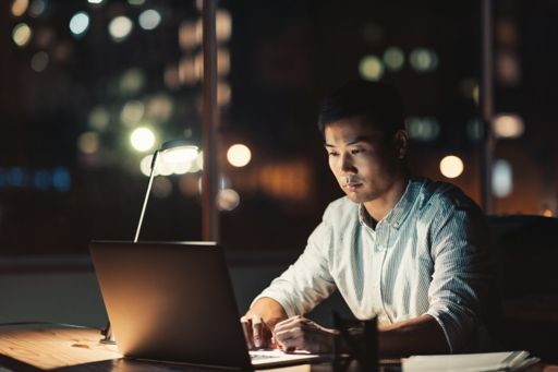 Asian businessman using a laptop at his desk at night