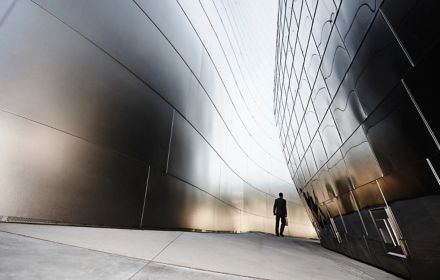 Man walking between two steel buildings