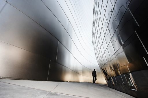 Man walking between two steel buildings