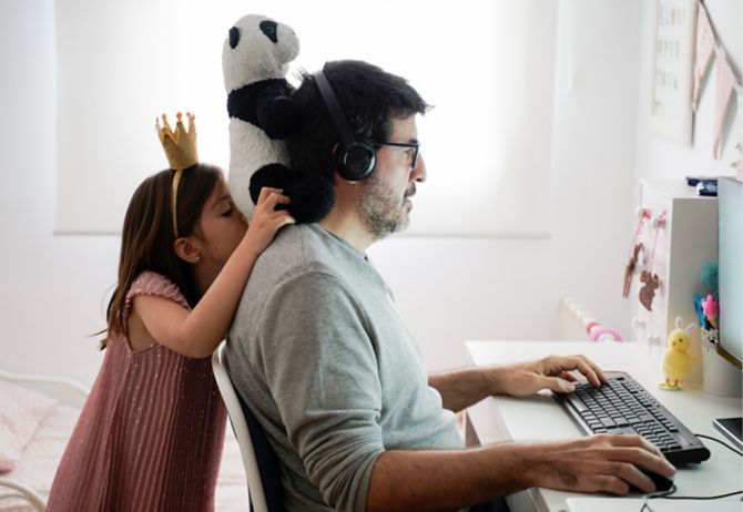 Man working on computer while his daughter is playing