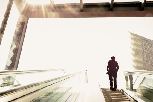 Person auf Rolltreppe im Sonnenlicht