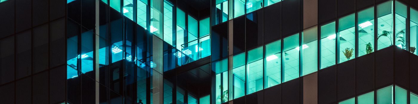 Modern office building glass windows glowing at night