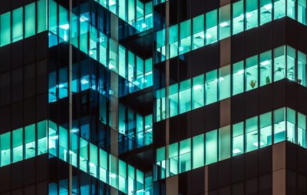 Modern office building glass windows glowing at night