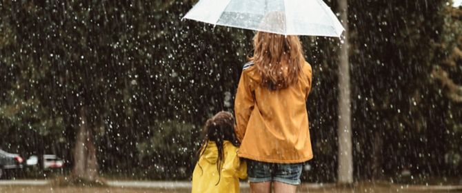 Mother daughter with umbrella in rain