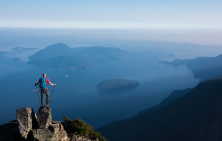 Mountain climber standing on top of cliff looking at the sea