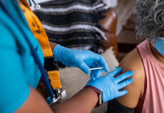 Nurse giving COVID-19 vaccine to woman