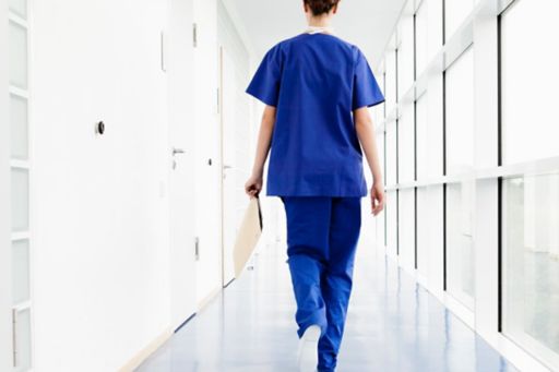 nurse walking through hospital corridor with document in hand markets