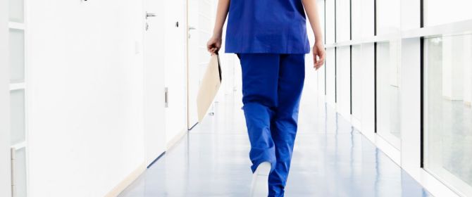  nurse walking through hospital corridor with document in hand