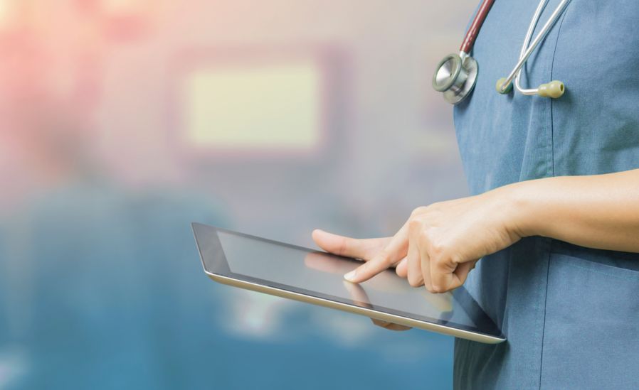 Nurse with stethoscope using tablet