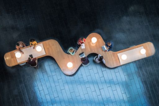 Panoramic overhead view of several business meetings going over curvy table