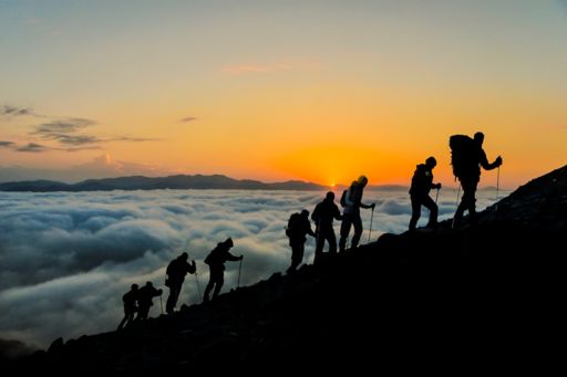 People climbing mountain at sunset