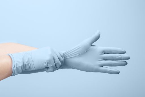 Niebieskie rękawiczki lateksowe zakładane na ręce