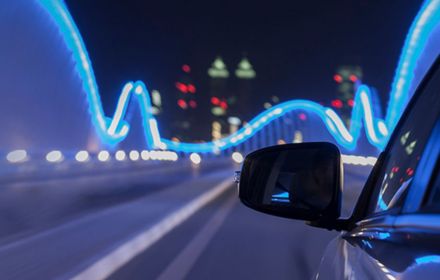 Rear view mirror of car on illuminated bridge
