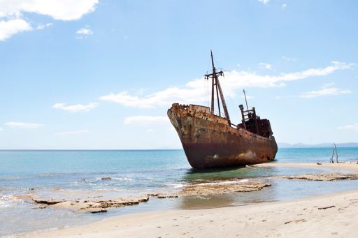 Rusting ship on sandy shore 