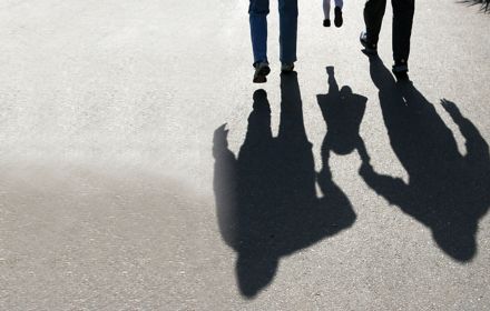 shadows behind two adults carrying a child