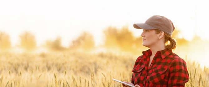 Female farmer in wheat field with smart device