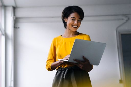 Smiling woman in yellow holding laptop