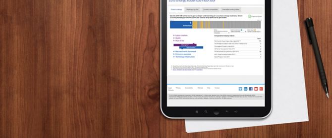 Tablet with KPMG site opened in browser, kept along with a paper and pen on a wooden background