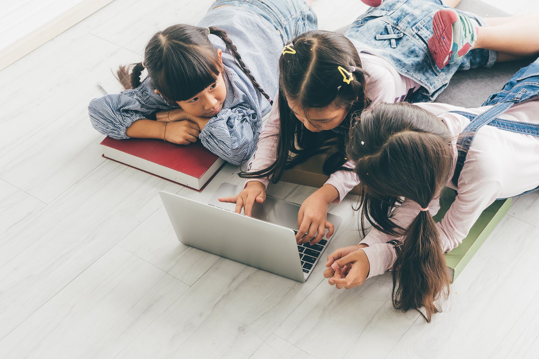 Three children on floor using laptop