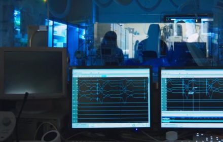 Three computer screens showing heart rate data in dark room