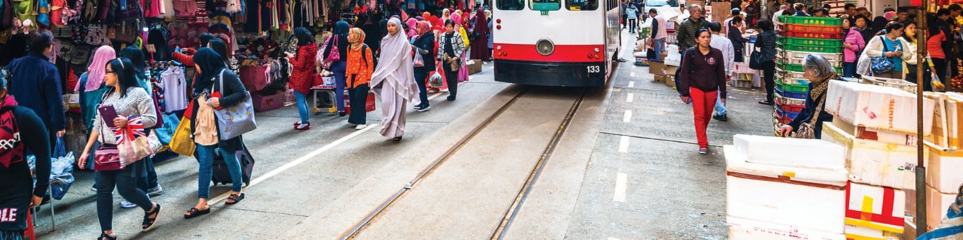 tram squeezes past shoppers and stalls