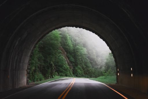 End of a tunnel opening in green foggy mountains