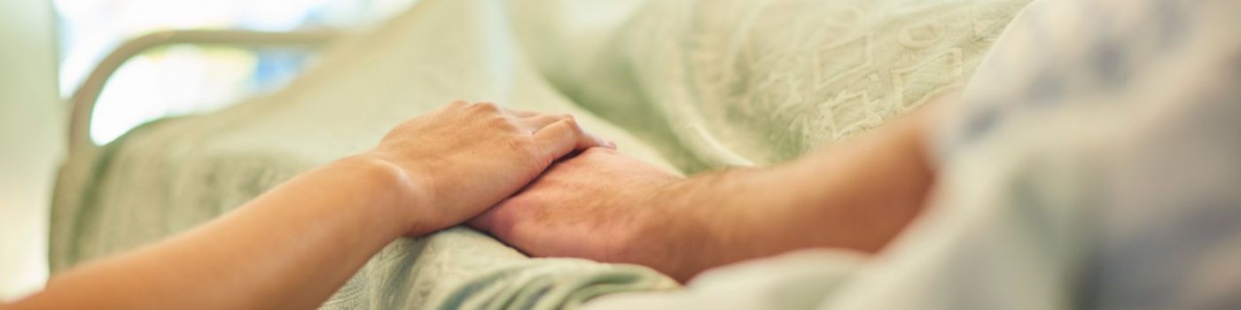 Visitor holds patient hand in hospital