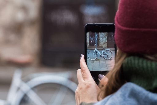Une femme prend une photo de son vélo avec son téléphone portable