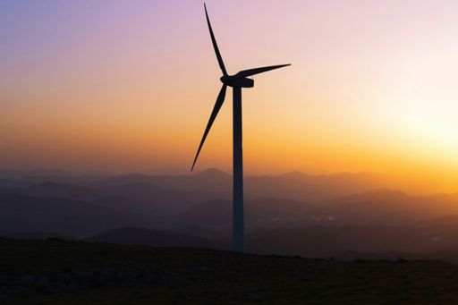 Wind turbine silhouette on mountain at sunset