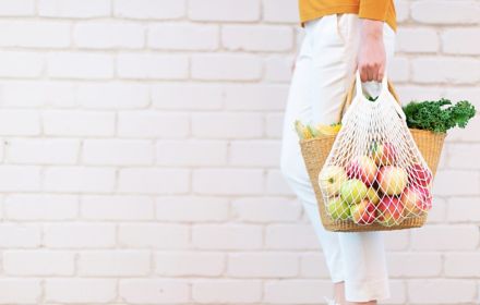 Woman carrying apples and grocery in bag