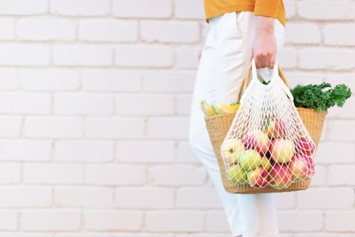 Woman carrying apples and grocery in bag