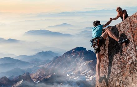 Woman helping a man in climbing mountain