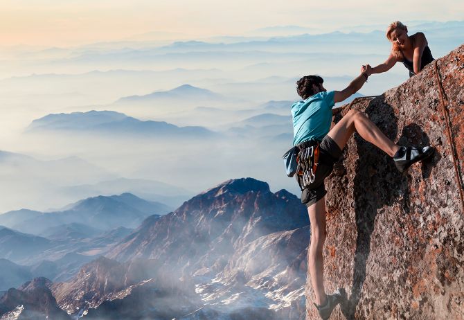 Woman helping man to climb on rock