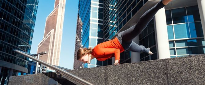 woman keeping balance on both hands in front of business buildings