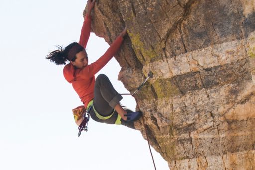 woman rock climbing up edge