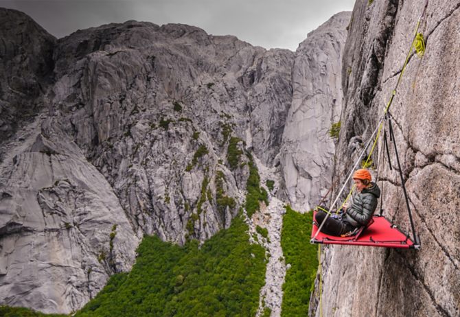 Woman sitting on the board hanging from a cliff