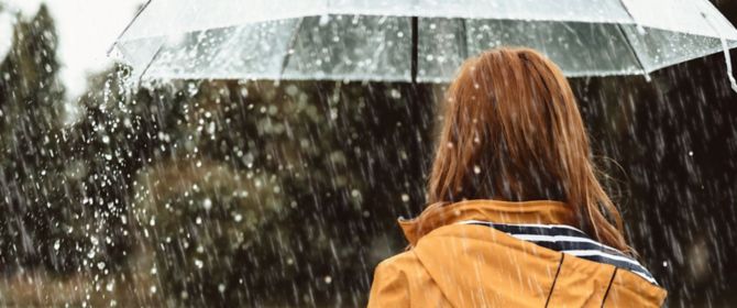 woman standing in rain under umbrella
