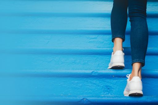 Woman wearing jeans walking up blue steps