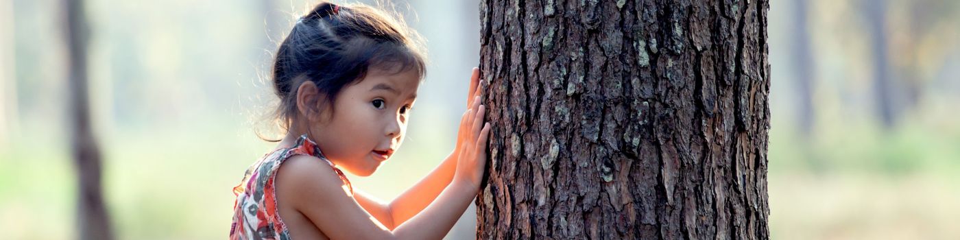 Young girl next to tree in forest