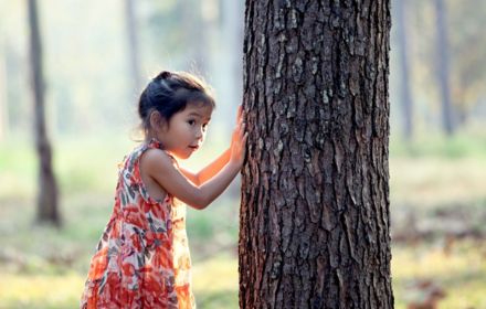 Young girl next to tree in forest