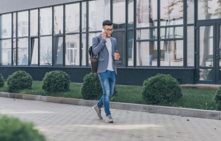 young man walking with phone in office park