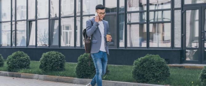 young man walking with phone in office park